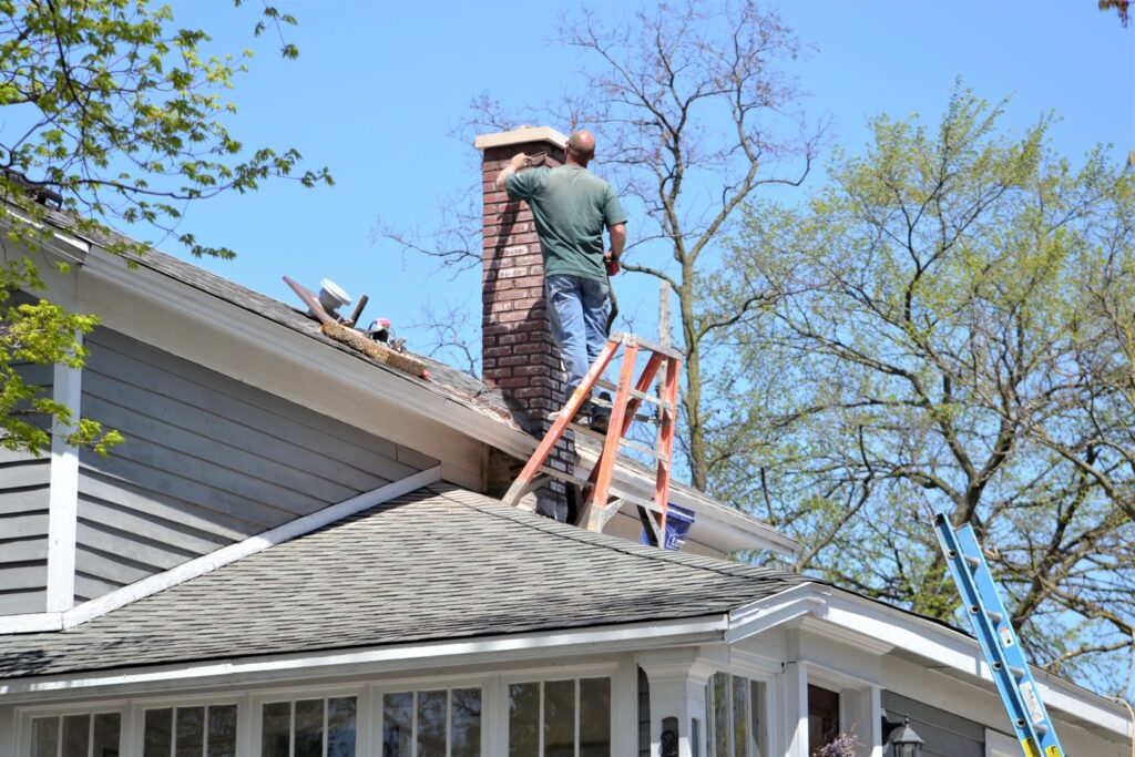 A professional chimney repair technician sealing cracks in a brick chimney to prevent fire hazards.